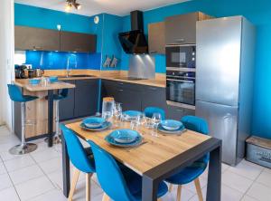 a kitchen with a wooden table and blue walls at Le Beluga XL - Confort et proximité Airbus in Colomiers