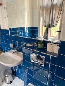 Un baño con azulejos azules, lavabo y espejo. en Apartment Siroka 14, en Praga