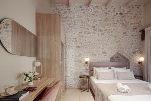 a bedroom with two beds and a stone wall at Philikon Luxury Suites in Rethymno
