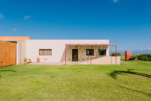 a white house with a grass yard at Trafalgar Polo Club in El Palmar