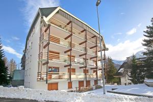 a white building with wooden balconies in the snow at Studio Genzianella Ski In-Ski Out 100m - Happy Rentals in Sestriere +19 photos