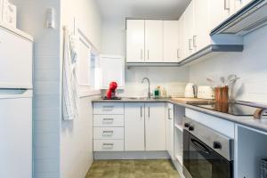 a white kitchen with white cabinets and a sink at Perfekt lokation! Gå til strand, restaurant og by in Sitio de Calahonda
