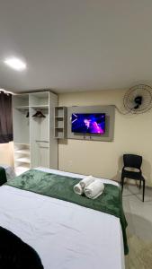 a bedroom with a bed and a tv on the wall at Lofts HOME Cabo Frio in Cabo Frio
