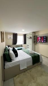 a bedroom with a large bed with green and white pillows at Lofts HOME Cabo Frio in Cabo Frio