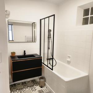 a bathroom with a sink and a tub and a mirror at Le CoCon palois in Pau