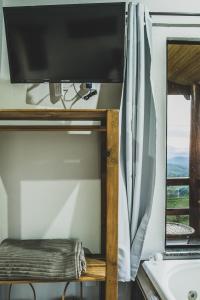 una televisione su un supporto in un bagno con una finestra di Chalé Alvorada Mirante Refúgio a Itamonte