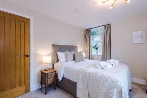 a bedroom with two beds with white sheets and a window at Rock Mill - Superior 2-Bedroom Apartment in Stoney Middleton