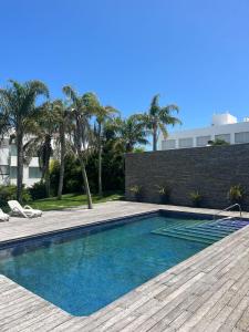 - une piscine avec une terrasse en bois et des palmiers dans l'établissement Esturion de Montoya, à Punta del Este