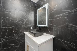 休斯顿Comfy 2BR in Prime Spot with Free Parking and Pool的黑色瓷砖浴室设有水槽和镜子