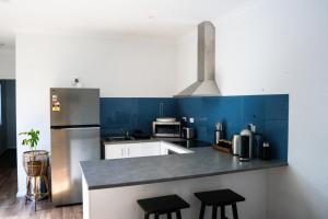 a kitchen with blue walls and a counter with stools at The Salthouse in Quindalup