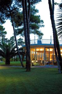 TH Tirrenia - Green Park Resort في تيرّينيا: منزل به الكثير من النوافذ والأشجار