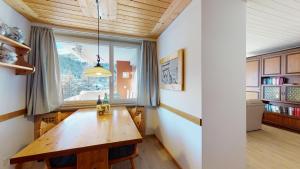 a dining room with a wooden table and a window at Apartment Skyline 307 in St. Moritz
