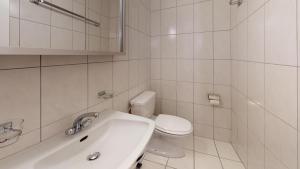 a white bathroom with a toilet and a sink at Apartment Skyline 307 in St. Moritz +4 photos
