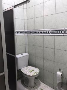a bathroom with a toilet in a tiled room at Casa da vila in Imbituba