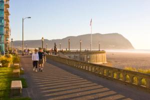 two people walking down a sidewalk next to the beach at Beach Escape, 2 Blocks Away, Sleeps 6 in Seaside