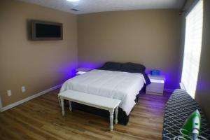 a bedroom with a white bed with a bench and purple lights at The Trace Elegant Eclectic Home with patio in Smyrna Ga in Smyrna