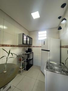 Una cocina con un refrigerador blanco y una mesa. en Quarto Eliote, en Aracaju