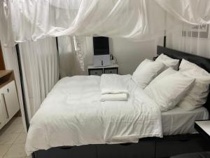 a bedroom with a white bed with white sheets and pillows at Appartement luxueux Ngousso Yaoundé in Yaoundé