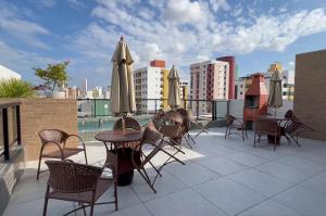 a patio with chairs and tables and umbrellas on a roof at Flat Genebra Bessa 2 Quartos 4 Pessoas 150m Praia in Tambaú