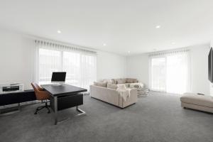 a white living room with a piano and a couch at Inlet Paradise in Rhyll