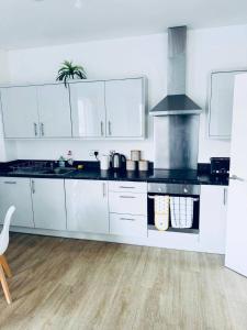 a kitchen with white cabinets and a stove top oven at Cosy City Apartment in Manchester in Manchester +7 photos