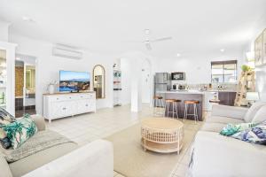 a living room with white furniture and a kitchen at Dasheri at Mango Lagoon Resort in Palm Cove