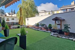 a garden with a lawn with plants and an umbrella at Charmant appartement hyper central, idéal pour couple ou petite famille, parking couvert in Crans-Montana +18 photos
