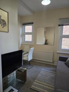 a living room with a flat screen tv and a desk at Stylish 1 bed apartment in Watford