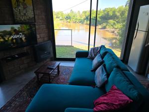 a blue couch in a living room with a view of a river at Casita Mirador Casai in Oliveros