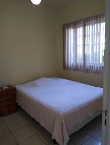 a bedroom with a white bed and a window at Casa na Serra Temporada in Petrópolis