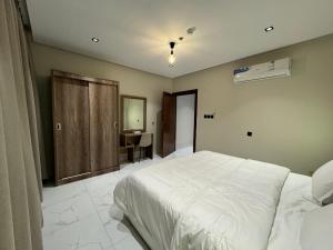 a bedroom with a white bed and a desk at اجنحة العريني suites aloraini in AlUla