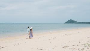a man and a woman walking on the beach at Villa Sirene Ishigaki in Ishigaki Island