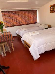 a room with three beds and a table and a window at ENEDE HOSTEL in Cusco