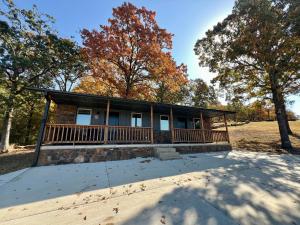 a house with a porch with trees in the background at The Rocky Retreat in Cookson