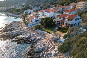 grupa domów na skalistym wzgórzu obok wody w obiekcie Apartments by the sea Milna, Vis - 8946 w mieście Rukavac +13 zdjęć