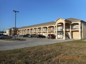 a large building with cars parked in a parking lot at Crossroads Inn & Suites in Victoria