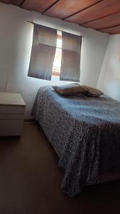 1 dormitorio con cama con almohada y ventana en Jardim Aruan, en Caraguatatuba