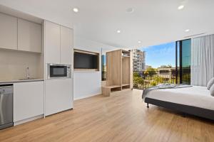 a bedroom with a bed and a kitchen with a balcony at Rambla at Story House in Brisbane