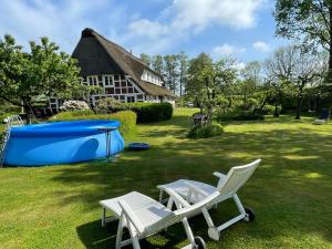 dos sillas blancas y una bañera azul en un patio en Kamin Ofen Wohnung -Altes Landhaus Oste- 2 Schlafzimmer, Terrasse, Grill, Küche, Bad, WLAN, nah am Nordsee Strand, en Hemmoor