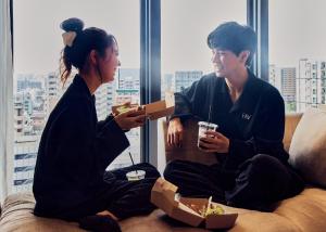 鹿児島市にあるFAV LUX 鹿児島天文館のソファに座って食べ物を食べる男女