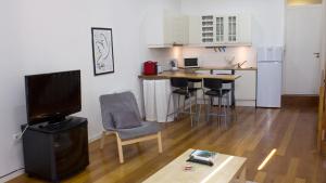 a living room with a television and a kitchen at Porto Beach House in Porto