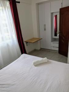 a bedroom with a white bed and a table at centennial in Eldoret