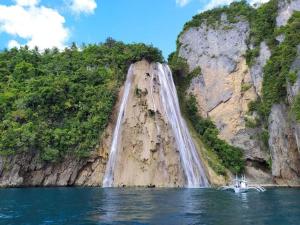 a boat in the water in front of a waterfall at Maria Kulafu Studio Apartment Kinamaligan- Beside Eglin Gas FREE Wifi in Masbate