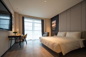 a bedroom with a large bed and a desk and a table at Atour Hotel Zigong Huashang International City Summit Park in Zigong