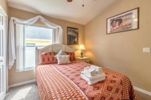 a bedroom with a bed with a orange comforter and a window at Safari Lodge in Orlando