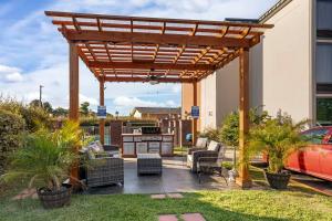 a patio with a wooden pergola with chairs and a table at Best Western New Albany in New Albany