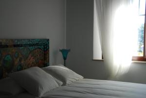 a bedroom with a bed with white sheets and a window at Casa Millán in Puerto-Moral