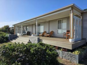 una casa con un porche de madera con sillas. en Coorong Lakeside Cottage, en Meningie