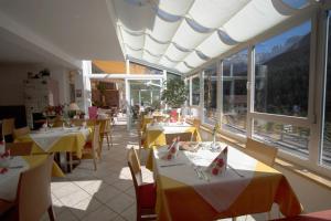 a restaurant with tables and chairs with yellow tables and windows at Gasthof Edelweiss in Tires