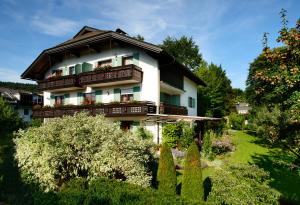 a house with balconies and a yard with trees at Haus Elisabeth, Appartements in Krumpendorf am Wörthersee